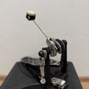 Fotografie zachycuje mechanické příslušenství z kovových a plastových částí s černým řetězem. Sestava obsahuje kovovou páku s bílým knoflíkem, pružin…