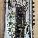 Fotografie zachycuje vnitřek elektronického zařízení v hliníkovém šasi. Uvnitř je vidět komplexní zapojení kabelů, kondenzátorů a dalších komponentů.…