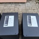 Dva černé subwoofery s texturovaným povrchem. Na horní straně každého přístroje je nalepený bílý papír s logem RCF a nápisy +1 YEAR WARRANTY EXTENSIO…