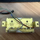 Fotografie znázorňuje spodní stranu elektrického snímače s kovovým krytem zlaté barvy. Na spodní části je vyražen nápis 58/15LT™, TREBLE a TCI K, dál…