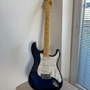 Elektrická kytara s tmavě modrým přechodovým lakem a bílým perleťovým pickguardem. Na hlavě hmatníku je viditelné logo Squier. Krk a hmatník jsou vyr…