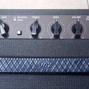 Detail horní části černého kytarového komba s ovládacím panelem. Na panelu jsou nápisy INPUT, GAIN, Overdrive Clean, TREBLE, BASS, VOLUME, HEAD / LIN…