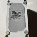 Spodní strana bílého efektového pedálu s čtyřmi gumovými nožičkami a šrouby v rozích. Uprostřed je nálepka s logem MHpedals a textem: Hand Made In CZ…