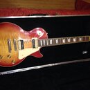Elektrická kytara s trupem v červeně-žlutém sunburst provedení a viditnou strukturou dřeva. Nástroj má dva humbuckery, bílý pickguard a čtyři ovládac…