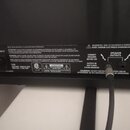 Fotografie zachycuje zadní panel černého elektronického zařízení s několika nápisy a konektory. Jsou zde vidět texty „MAINS INPUT“, „FUSE“ a „SPEAKER…
