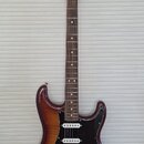 Elektrická kytara s trupem v hnědém sunburst provedení a černým pickguardem. Na hlavě hmatníku je viditelné logo "Squier". Nástroj má tři snímače typ…