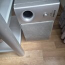 Stříbrný subwoofer s texturovanou přední mřížkou. Na horní části je vidět logo YAMAHA a nápis NSWD. Povrch skříně vykazuje drobné škrábance a opotřeb…