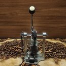 Stříbrný kovový pedál bicího bubnu s řetízkovým pohonem. Na horní části je umístěna dlouhá páka s kulatým světlým koncem. Na nástroji nejsou žádné vi…