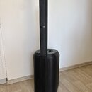 Černý sloupový reproduktorový systém složený z nízkofrekvenčního subwooferu a nasazeného lineárního hornu. Na sloupci je umístěno malé bílé logo, kte…
