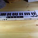 Bílá klaviatura s 37 klávesami. Na přední hraně je nápis KEYSTEP 37 a pod ním text CONTROLLER & SEQUENCER, v pravém rohu je logo (A.). Vlevo na horní…