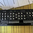 Černý analogový syntetizátor s nápisem SE-02 STUDIO ELECTRONICS a logem Roland. Přední panel obsahuje numeroustočítka, přepínače a sekci s klávesovým…