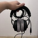 Černé kabelové sluchátka s šedými polštářky. Na pravém náušníku je vidět nápis "Sennheiser". Sluchátka jsou v zachovalém stavu, kabel je srolovaný do…