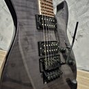 Elektrická kytara s tmavě šedým průsvitným lakem a viditnou strukturou dřeva. Je vybavena dvěma humbuckery a černým tremolo mostem s nápisem Floyd Ro…