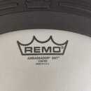 Bílá bubenová blána s černým potiskem. Je na ní viditelné logo REMO® v podobě koruny a nápisy AMBASSADOR® SMT™, COATED a MADE IN U. S. A. Povrch blán…