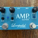 Modrý kytarový efekt s bílými nápisy AMP™ ELEVEN a Lovepedal CUSTOM EFFECTS. Na horní straně jsou tři černé otočné knoflíky s popisky LEVEL, DRIVE a…