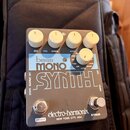 Kytarový efekt pedál v šedé barvě s bílým nápisem SYNTH. Na horní části je modrý štítek s textem bass MONO a čtyři bílé otočné knoflíky s popisky DRY…