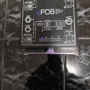 Černá pasivní DI box s bílým nápisem dPDB Dual Passive Direct Box a logem ART APPLIED RESEARCH AND TECHNOLOGY. Na povrchu je schéma zapojení s označe…