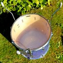 Fotografie zachycuje buben s transparentním průsvitem korpusu a kovovými obručemi. Na horní bláně je v horní části umístěno logo SONOR. Buben je vyba…