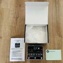 Fotografie zobrazuje efekt pedál značky electro-harmonix, model 22000 Dual Stereo Looper, v černé barvě s kovovým povrchem. Vedle pedálu je otevřená…