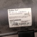Detailní záběr na bílou nálepku s technickými údaji nalepenou na šedém plastovém povrchu. Na nálepce je text Guitar Set, RF BAND: V-A-50mW, 790.000-8…