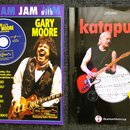 Fotografie zobrazuje dvě publikace: vzdělávací materiál pro kytaru a zpěvník. Vlevo je modrý sešit s nápisy JAM with GARY MOORE, Guitar Tablature a T…