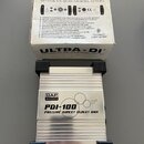 Fotografie zobrazuje stříbrnou kovovou pasivní DI box s černými plastovými zátlačkami na koncích. Na horní straně je nápis DAP AUDIO a model PDI-100…