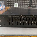 Černý grafický ekvalizér v rackovém provedení s řadou posuvníků. Na předním panelu je nápis PEQ-1215H Dual 15 Band Graphic Equalizer a logo SHOW. Pod…