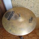 Zlatý činel typu crash umístěný na kovovém stojanu. Na povrchu jsou čitelné nápisy SABIAN a AAX STAGE CRASH 16"/40cm. Povrch vykazuje drobné nečistot…