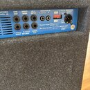 Záhlaví modrého zesilovače s řadou vstupů a výstupů. Jsou zde nápisy LINE OUT, EFFECT SEND, LO-Z INPUT, MONITOR IN L (mono) R, BALANCED OUTPUT a TUNE…