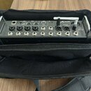 Černý digitální mixér v černé přepravní tašce. Na přístroji jsou nápisy XAIR, XR12 a logo behringer. Zadní strana obsahuje různé vstupy a výstupy s o…