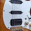 Detail elektrické kytary s bílým pickguardem a tělem v žlutohnaté barvě. Nástroj má tři černé snímače, z nichž každý nese bílý nápis Seymour Duncan.…