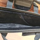 Fotografie zachycuje otevřený černý softcase z textilního materiálu. Vnitřní prostor je vyložen černým plyšovým materiálem, na kterém jsou vidět drob…