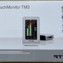 Krabice s nápisem TouchMonitor TM3 a logem RTW. Na obrázku je zobrazen stříbrný přístroj s displejem, který zobrazuje barevnéy měřiče úrovně a ovláda…