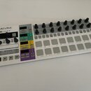 Bílá kontrolní jednotka s nápisem ARTURIA YOUR EXPERIENCE - YOUR SOUND. Zařízení obsahuje několik řad šedých čtvercových tlačítek, černých otočných p…