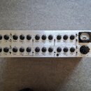 Stříbrný rackový procesor s nápisem TUBE ULTRA-G. Přední panel obsahuje dvě řady černých otočných ovířků s popisy jako FREQUENCY, BANDWIDTH a LEVEL.…