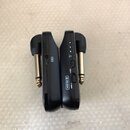 Dva černé plastové bezdrátové vysílače s kovovými konektory. Na jednom je vidět USB port a symbol blesku, na druhém nápisy ON, OFF, UNLOCK a řada čís…