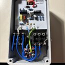 Interiér efektového pedálu v šedém kovovém šasi. Na bílé desce s elektronickými součástkami je nápis M pedals Clean BOOST a v levém dolním rohu kód 9…