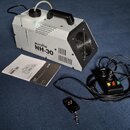 Bílý mlhový stroj s černou rukojetí a ventilátorem v zadní části. Na boku je nápis eurolite NH-30 a pod ním menší text, který není plně čitelný. K za…