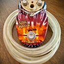 Efekt Talk Box značky Danelectro s barevným motivem tie-dye v červených, žlutých a modrých odstínech. Na horní straně jsou dva otočné oválné knoflíky…