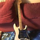 Bílá elektrická kytara typu Stratocaster s černým pickguardem a světlou hmatníkovou deskou. Na hlavě je nápis „Silver Star“ a logo „Toma“. Nástroj má…