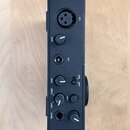 Černý zvukový interface s kovovým povrchem. Na přední straně jsou vstupy označené jako IN 1 (XLR konektor) a IN 2 (jack konektor), dva ovratidla s ná…