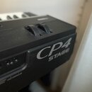Detailní záběr na černý digitální klavír s texturou povrchu. Na boku je viditelný stříbrný nápis CP4 STAGE a dvě ovládací kolečka. V dolní části jsou…