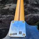 Zadní strana elektrické kytary s černým bodies a dřevěným hřádem. Na chromovaném krytu v místě spoje krku a těla je vyryto logo Fender a značka CE sp…