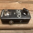 Černý kytarový pedál s nápisy tc electronic, TRUE BYPASS a LOOPER DITTO. Na horní straně se nachází stříbrný spínací pedal a černý otočný knoflík s n…