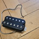 Černý humbucker s dvěma řadami bílých magnetických pólců. Nástroj nemá žádné viditelné značky ani nápisy. K pickupu vede stříbrně opletený kabel.