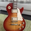 Elektrická kytara s trupem ve tvaru single-cut a barevným přechodem od červené k žluté (sunburst). Nástroj má dva humbuckery s krémovými rámečky, kré…