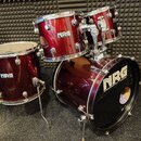 Tmavě červená bicí souprava tvořenca čtyřmi bubny. Na každém z nich je bílý nápis NRG, přičemž na basovém bubnu je doplněn text DRUMS. Nástroje mají…