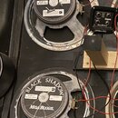 Dva reproduktory s černým papírem a šedými kovovými rámy, které vykazují známky opotřebení povrchu. Na obou jsou nápisy BLACK SHADOW, MESA BOOGIE a C…