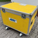 Žlutý transportní kufr s hliníkovými hranami a rohy. Na přední straně je bílý štítek s modrým nápisem ARRI a malým logem v kroužku. Kufr je vybaven d…