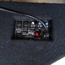 Fotografie zachycuje zadní panel aktivního monitoru v černém textilním potahu. Na ovládacím panelu jsou dva modré knofíky s nápisy VOLUME a BASS, vst…